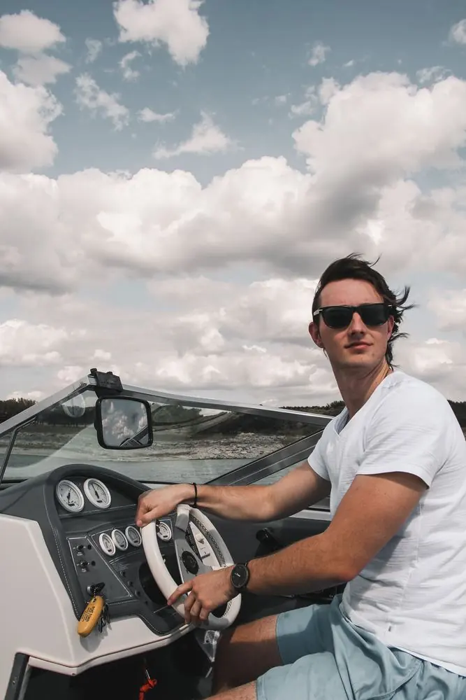 A man driving a powerboat under a big cloudy sky